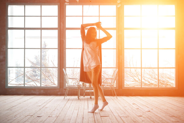 Attractive young woman dancing near huge wondows at her apartment