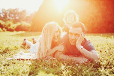 Mutlu genç aile dışarıda yeşil doğada birlikte vakit geçiriyor..