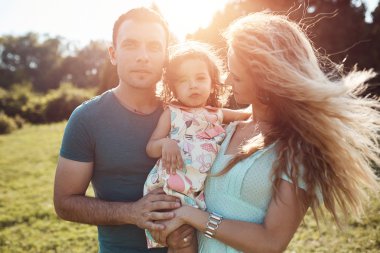 Mutlu genç aile dışarıda yeşil doğada birlikte vakit geçiriyor..