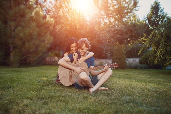 Pareja romántica sentada en la hierba en el jardín — Foto de Stock