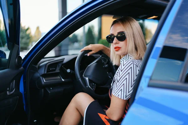 Femme en lunettes de soleil conduisant une voiture — Photo