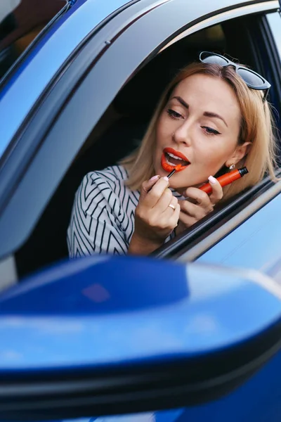 Femme regardant dans les voitures côté miroir et mettre du rouge à lèvres — Photo