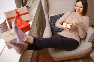 Elinde hediyeyle bir koltukta oturan bir kadın.