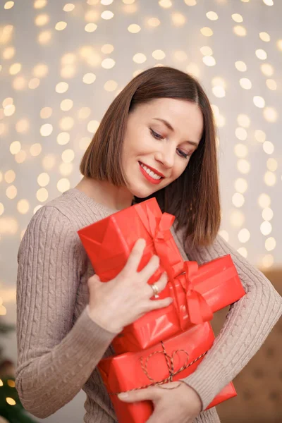 Hermosa mujer morena sosteniendo montón de cajas de regalo en la sala de estar decorada —  Fotos de Stock