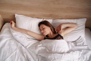 Beyaz kadın uyandıktan sonra yatakta geriniyor.