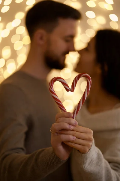 Pareja besando y mostrando la figura en forma de corazón de caramelos bastones caramelos —  Fotos de Stock