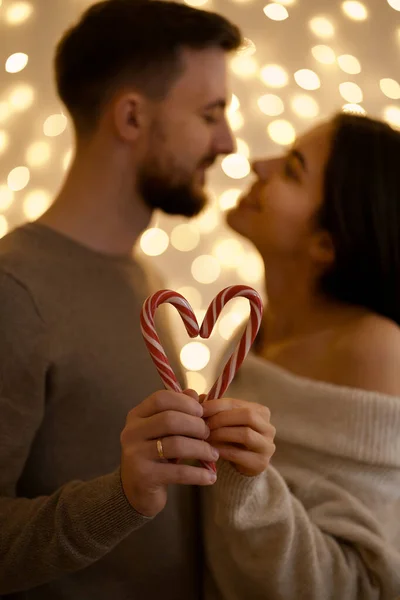 Pareja besando y mostrando la figura en forma de corazón de caramelos bastones caramelos —  Fotos de Stock