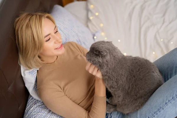 Young woman and cat on bed in the room — Stock Photo, Image