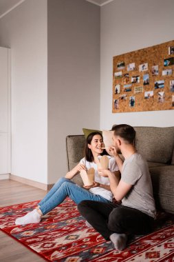 Gülümseyen adam ve kadın evde birlikte yemek yiyorlar.