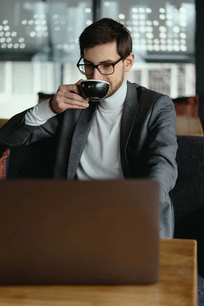 Homme d'affaires prospère travaillant sur ordinateur portable tout en buvant du café — Photo