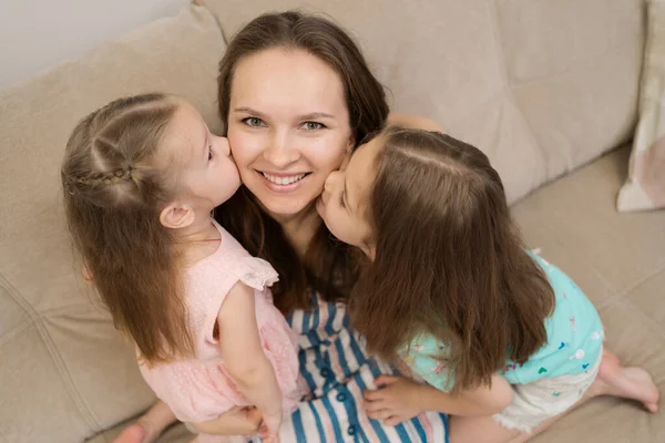 Две дочери целуют мамочку — стоковое фото