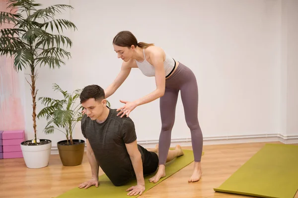 Yoga teacher and student practicing together in studio
