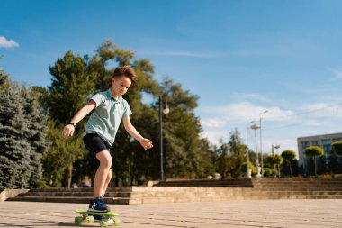 Sokakta kaykay süren bir çocuk.