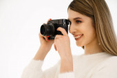 Usmívající se žena drží fotoaparát na bílém pozadí