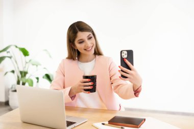 İçerde akıllı telefonu kullanan gülümseyen kadın.