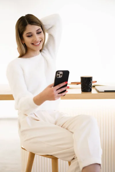 Усміхнена жінка говорить на смартфоні п'є каву в приміщенні — стокове фото