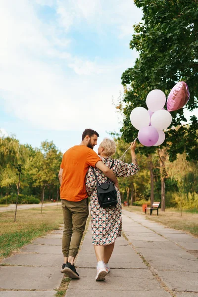 Mujer rubia y hombre con globos rosados — Foto de Stock