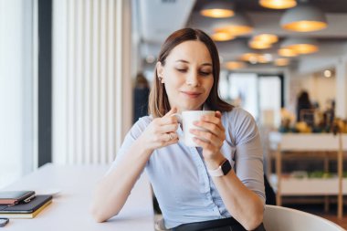 Kafede kahve içen genç bir kadının portresi.