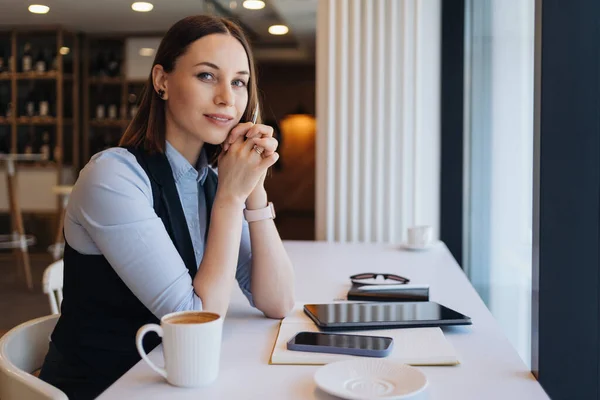 Femme réfléchie assise à la cafétéria avec un café tout en travaillant — Photo