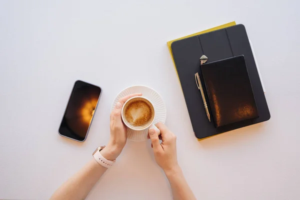 Top view vrouw handen met een kopje koffie, tablet, telefoon — Stockfoto