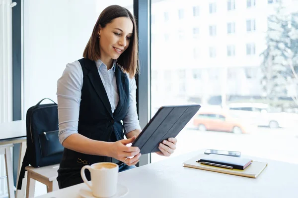 Portrait de jeune femme buvant du café à table avec tablette dans un café — Photo