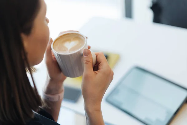 Portret van een jonge vrouw die koffie drinkt aan tafel met tablet in café — Stockfoto