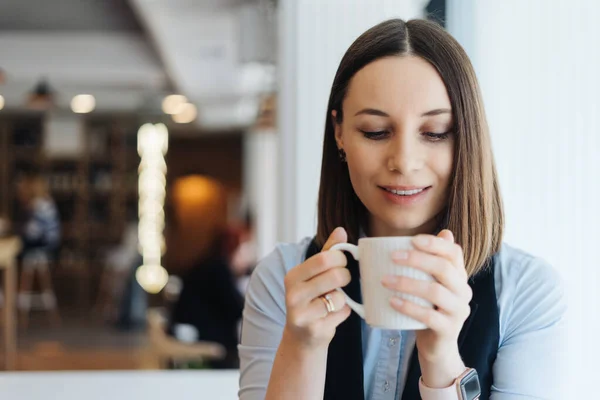 Portret van een jonge vrouw die koffie drinkt aan tafel in café — Stockfoto