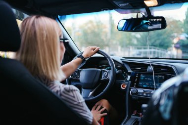 Güneş gözlüklü kadın araba kullanıyor.