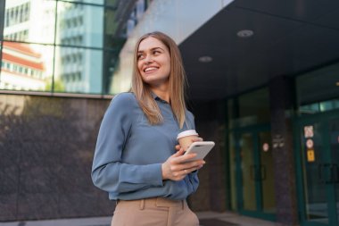 Modern akıllı telefon kullanan ve kahve içen bir kadın.