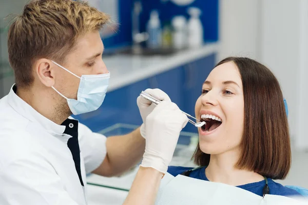 치과 의사는 진료소에서 기구를 사용하여 환자의 공동을 검사한다 — 스톡 사진