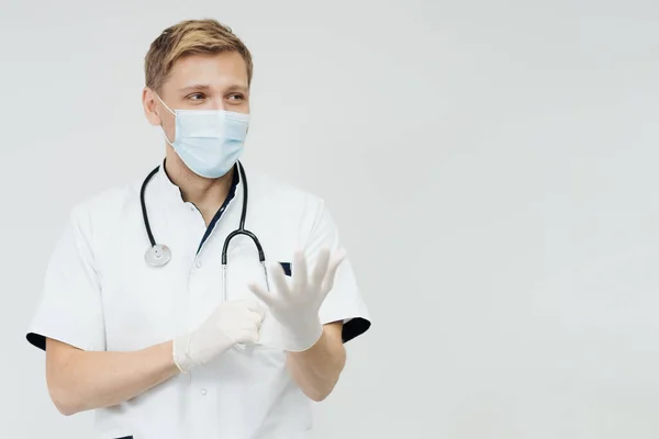 Портрет усміхненого доброзичливого лікаря, що надягає стерильні рукавички — стокове фото