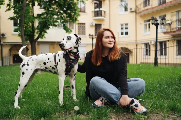 可愛いです女性ポーズと巨大ダルマチア犬上の街の背景 — ストック写真