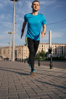 Şehirde koşan çekici fit bir adam.