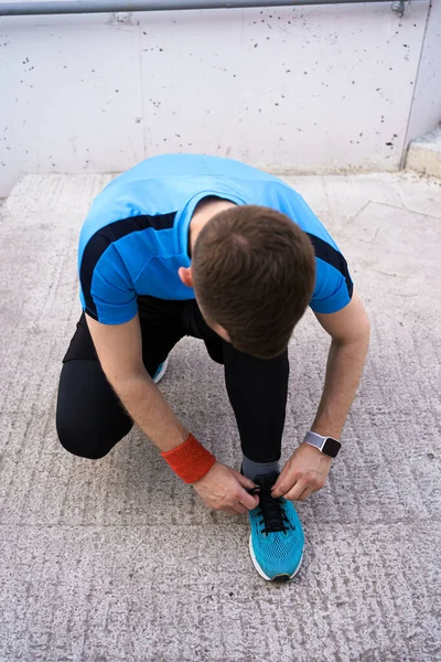 Man tying his sport shoes on concrete background