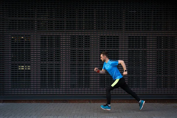 Hombre atlético corriendo en la calle urbana sobre fondo gris — Foto de Stock