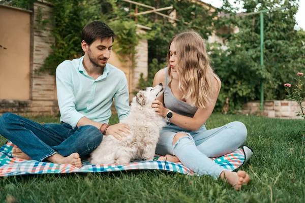 Belo casal com um cão na grama — Fotografia de Stock
