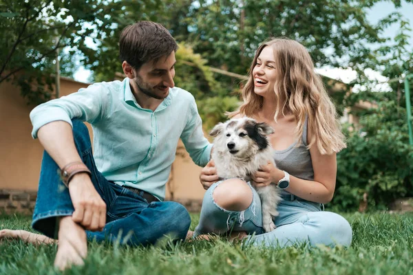 Çimlerin üzerinde köpeği olan güzel bir çift. — Stok fotoğraf