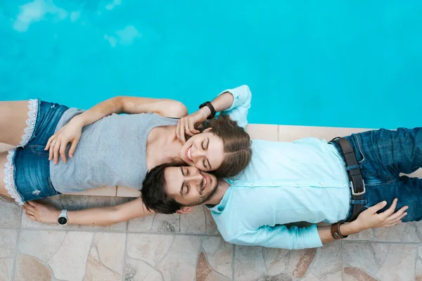 Amore coppia sdraiato vicino alla piscina — Foto Stock