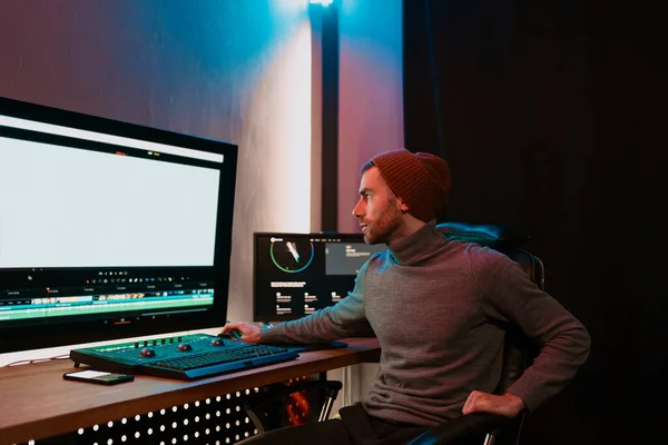Editor de vídeo masculino trabalhando em seu computador pessoal com grande exibição em branco — Fotografia de Stock