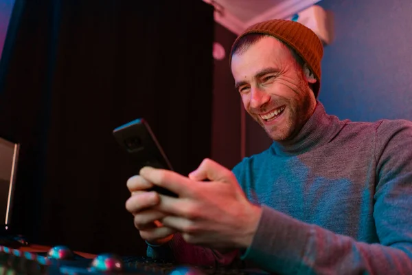 Hombre riendo retrato sosteniendo teléfono inteligente en su oficina en luces de neón — Foto de Stock