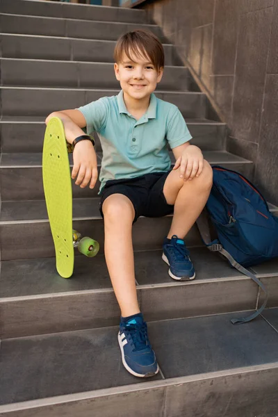 Niño sentado en las escaleras con una mochila y un centavo —  Fotos de Stock