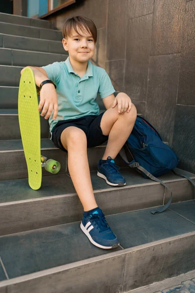 A fiú a lépcsőn ül egy hátizsákkal és egy pennyvel. — Stock Fotó