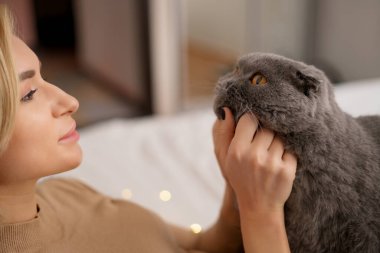 Genç kadın ve kedi yatakta.