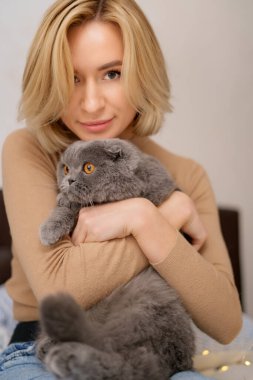 Genç kadın ve kedi yatakta.