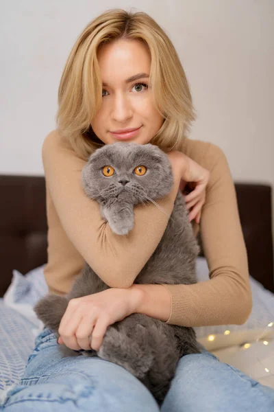 Young woman and cat on bed in the room