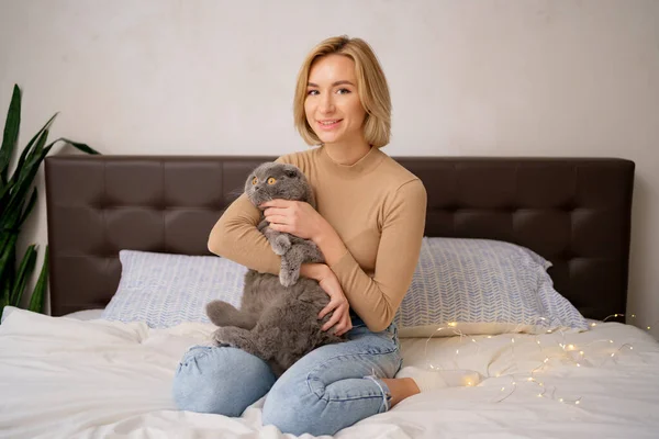Genç kadın ve kedi yatakta. — Stok fotoğraf