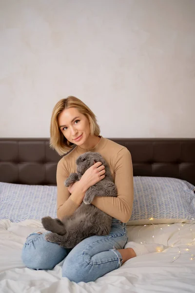 Jovem mulher e gato na cama no quarto — Fotografia de Stock