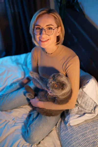 Junge Frau und Katze auf Bett im Zimmer — Stockfoto