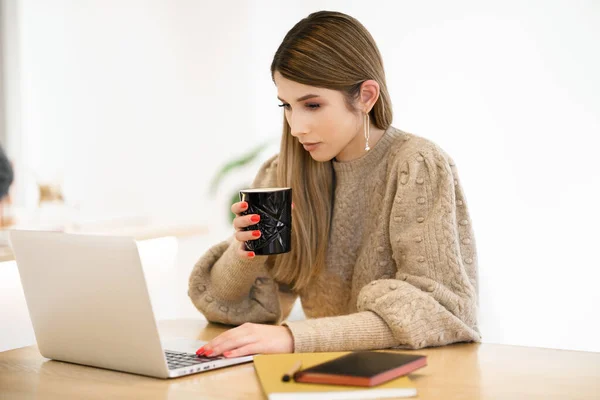 Jovem do sexo feminino no café usando laptop e beber latte — Fotografia de Stock