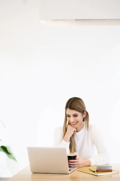Улыбающаяся белая женщина, работающая на ноутбуке — стоковое фото